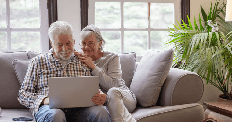 Senior couple on sofa reviewing laptop