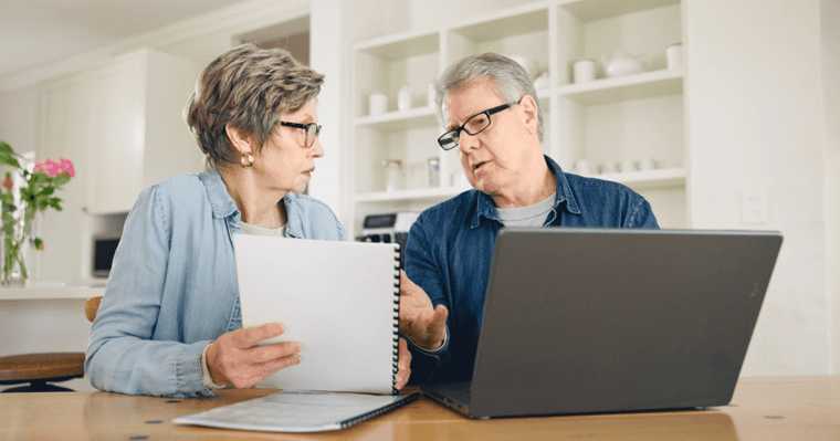 Senior couple sitting at table discussing the cost of assisted living.