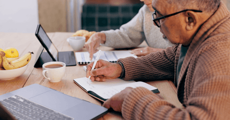 Elder couple at desk with computer trying to understand the cost of long-term care