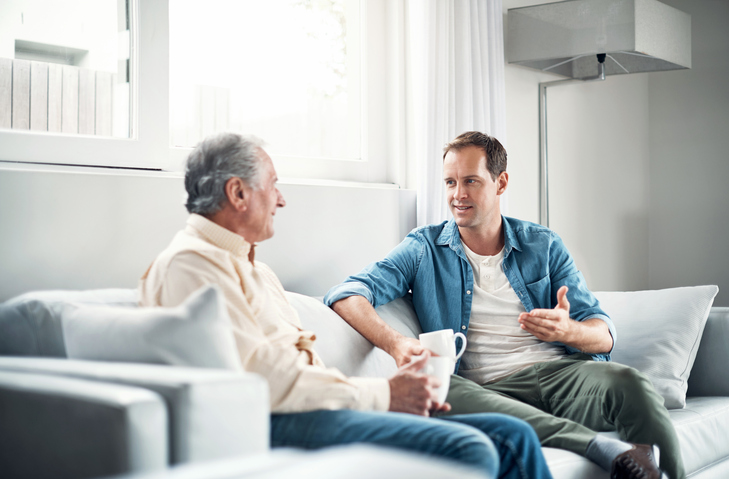 Adult male talking with his senior parent about assisted living