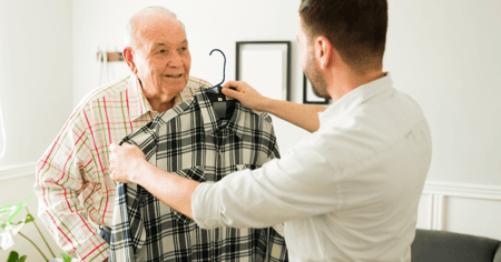 Questions to ask for assisted living young man holding a flannel shirt up to an older man