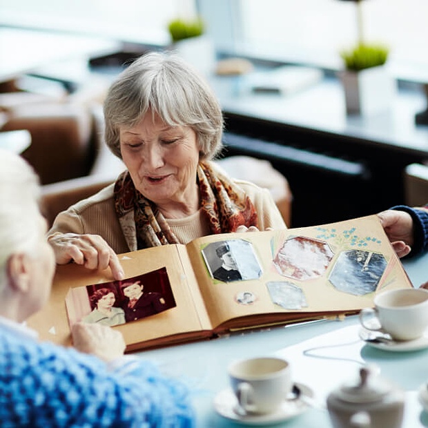Elderly women sharing old photos with one another.