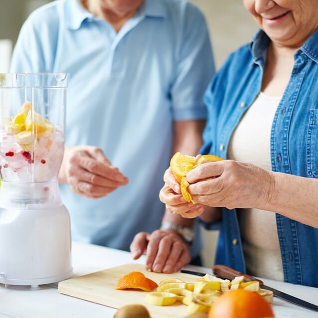 Man and woman working together to make fruit smoothies.