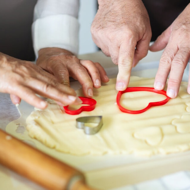 Close up of heart shape cookie cutters and dough.