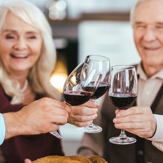 Group of friends toasting with glasses of red wine.