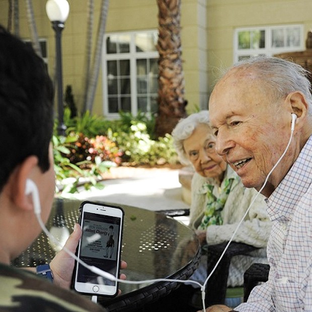 Grandkid sharing headphones with grandparent.