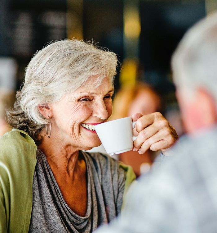 Woman smiling while drinking coffee.
